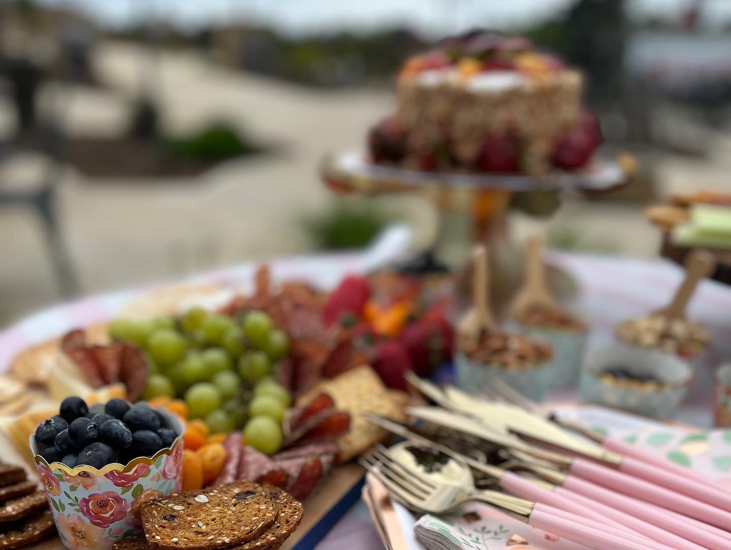 Outdoor grazing display with charcuterie, fruit and serving accessories
